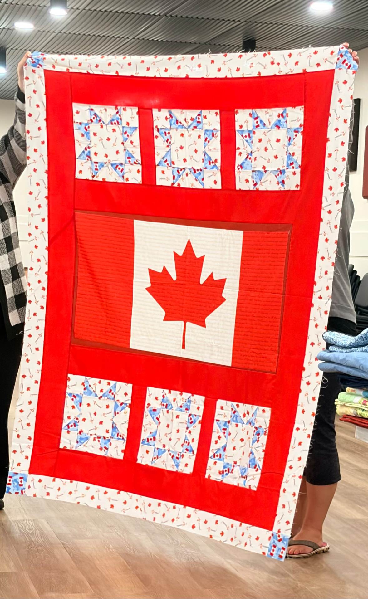 Canada flag quilt with a red maple leaf panel framed by red borders and star blocks