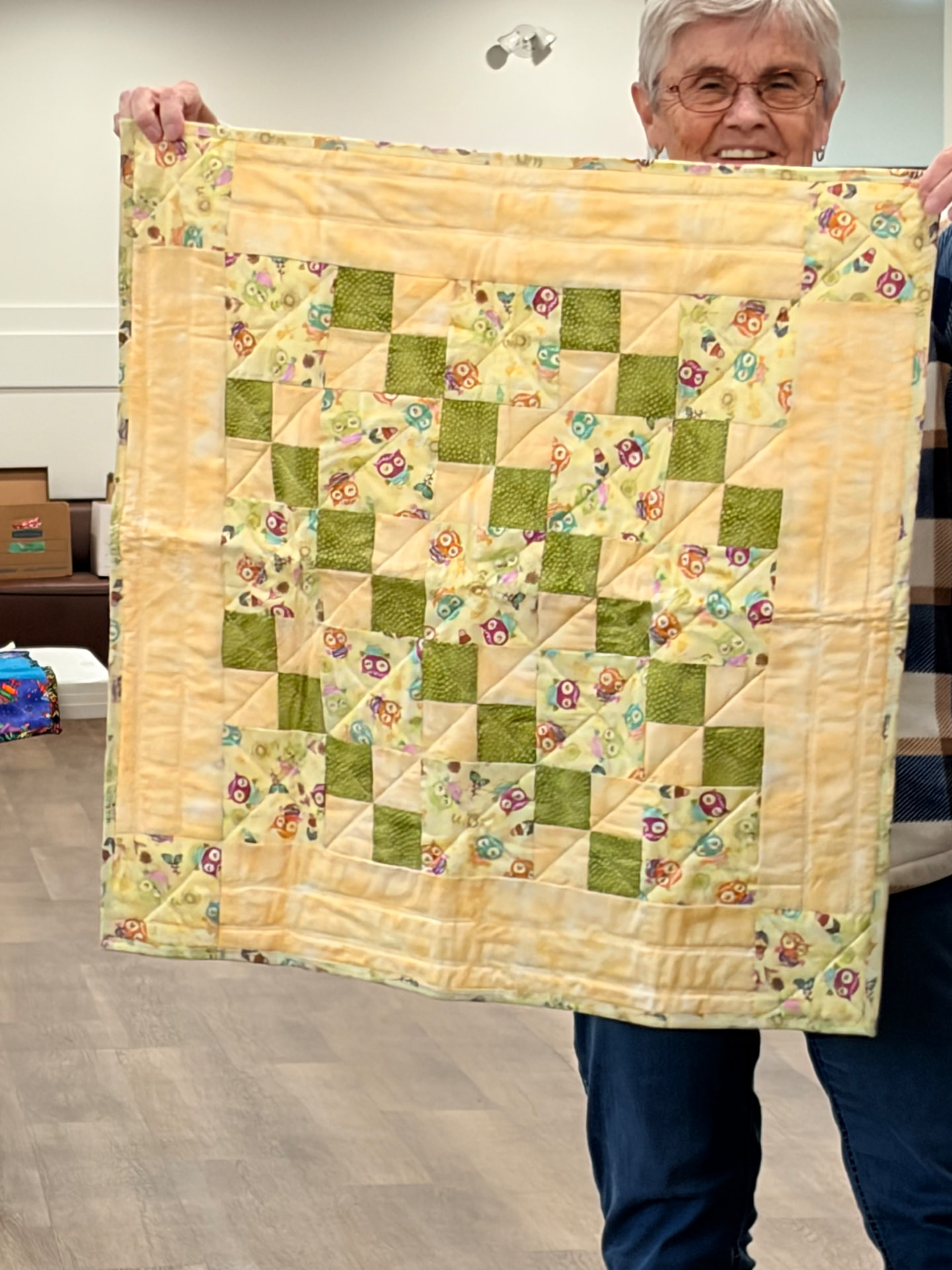 Owl-print quilt in greens and yellows with a buttery yellow border