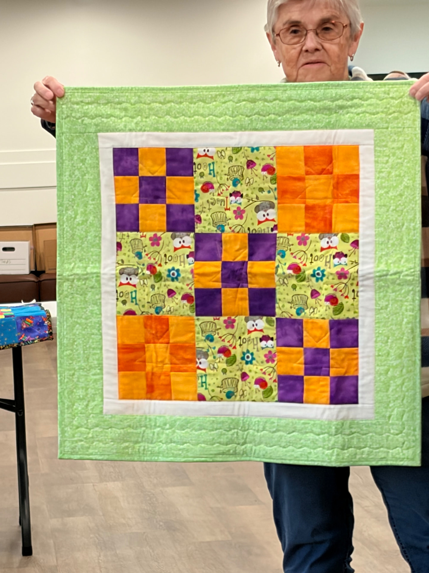 Nine-patch quilt in orange, purple, and owl prints with a green border