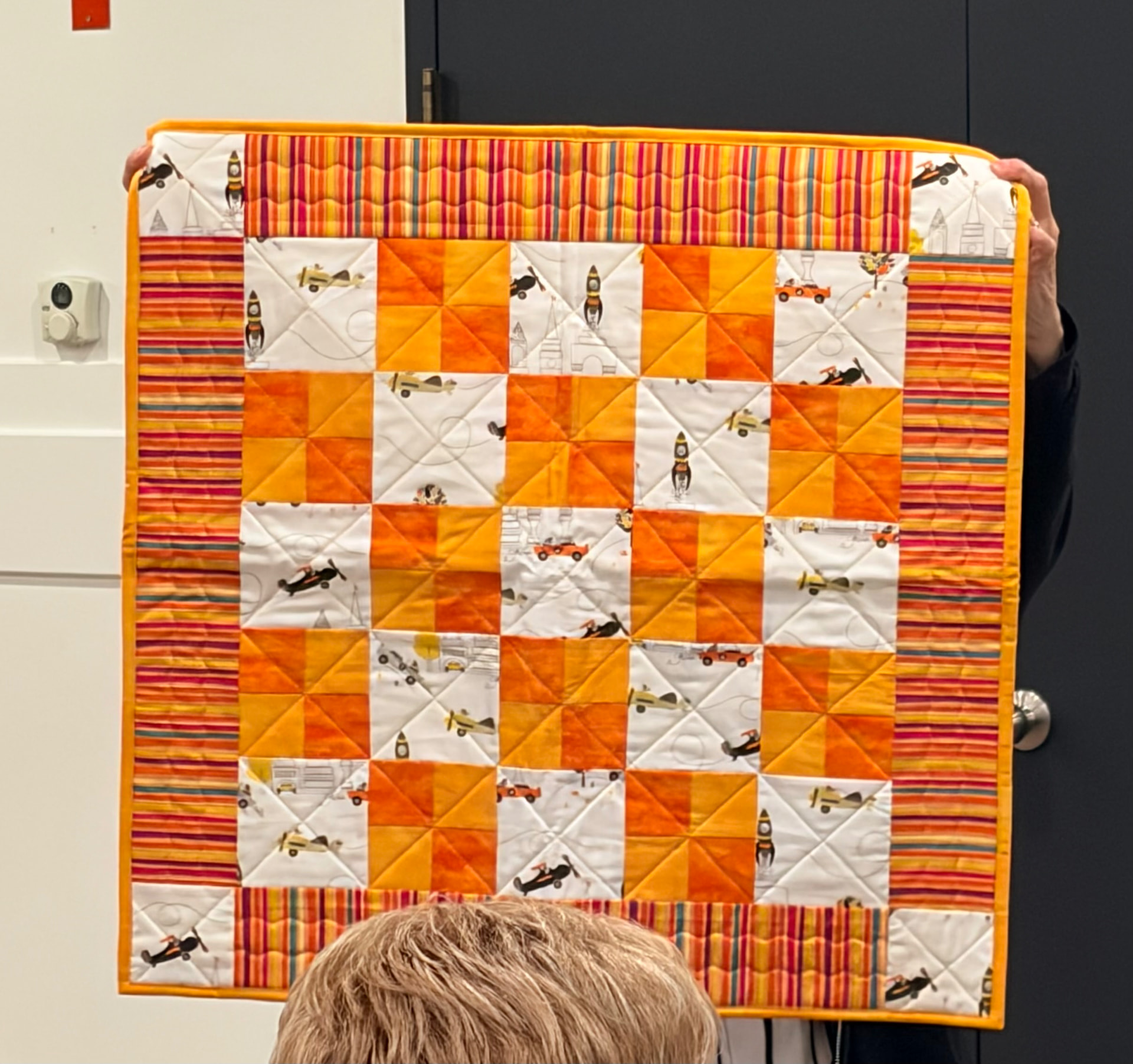 Orange pinwheel baby quilt with rocket and airplane fabric