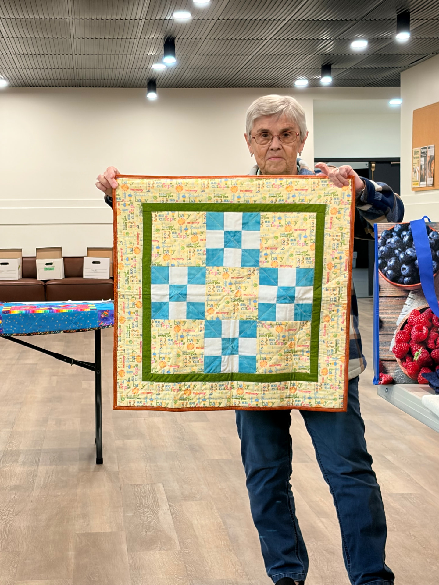 Nine-patch baby quilt in yellows and blues with a green and orange border