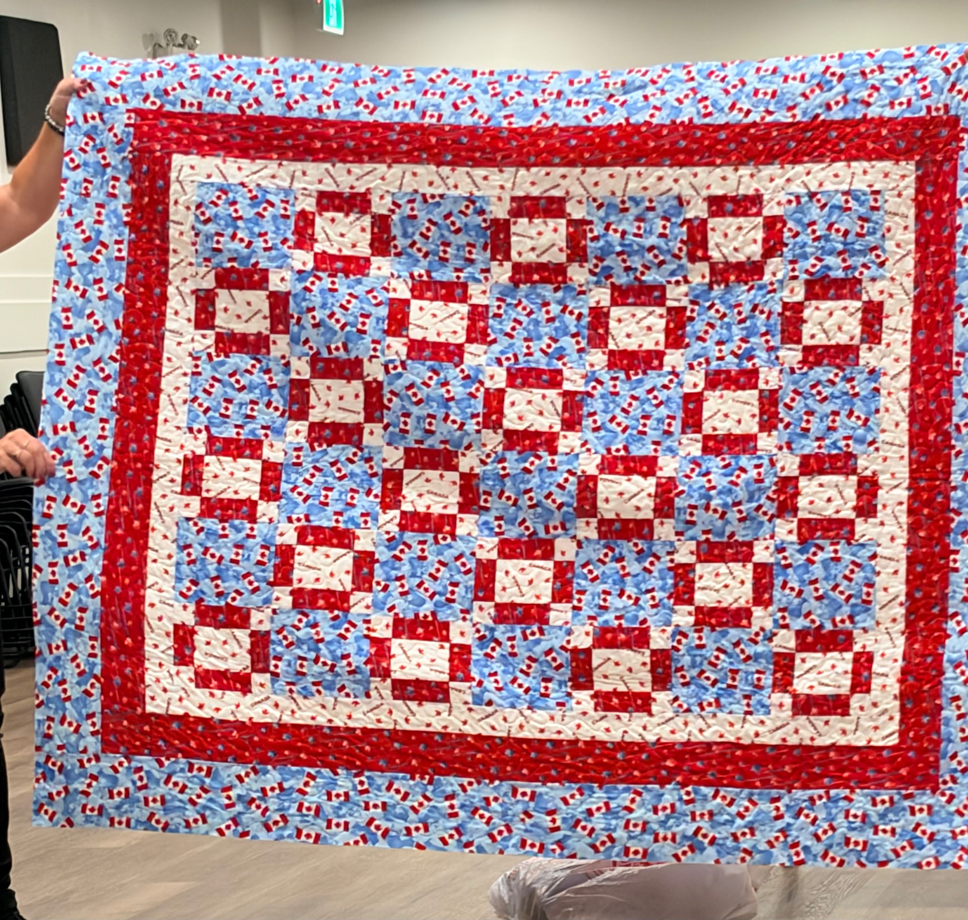 Canada flag quilt with red maple leaf log cabin blocks and a checkered border