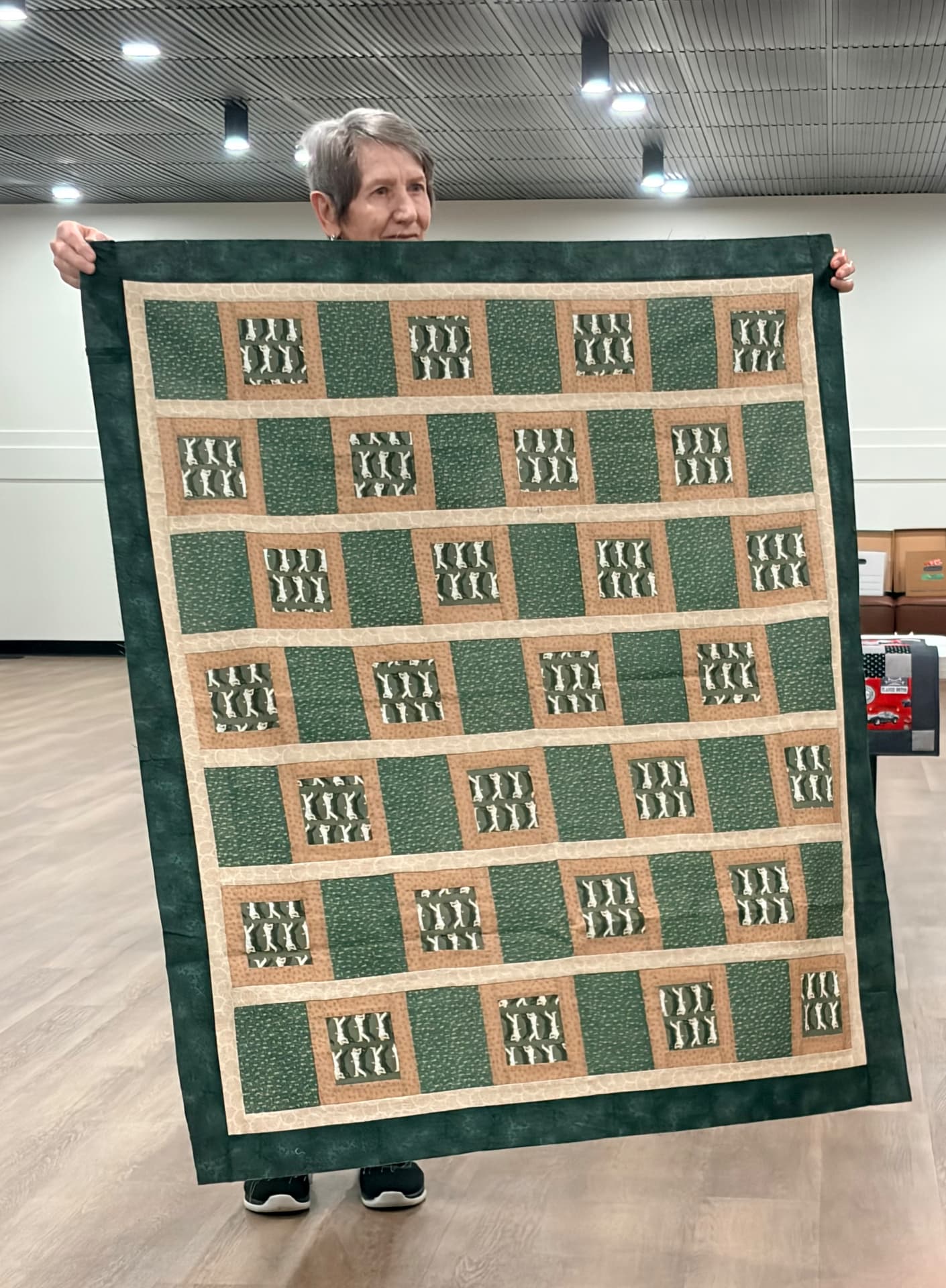 Cat-print windows quilt in green and brown tones with a deep green border