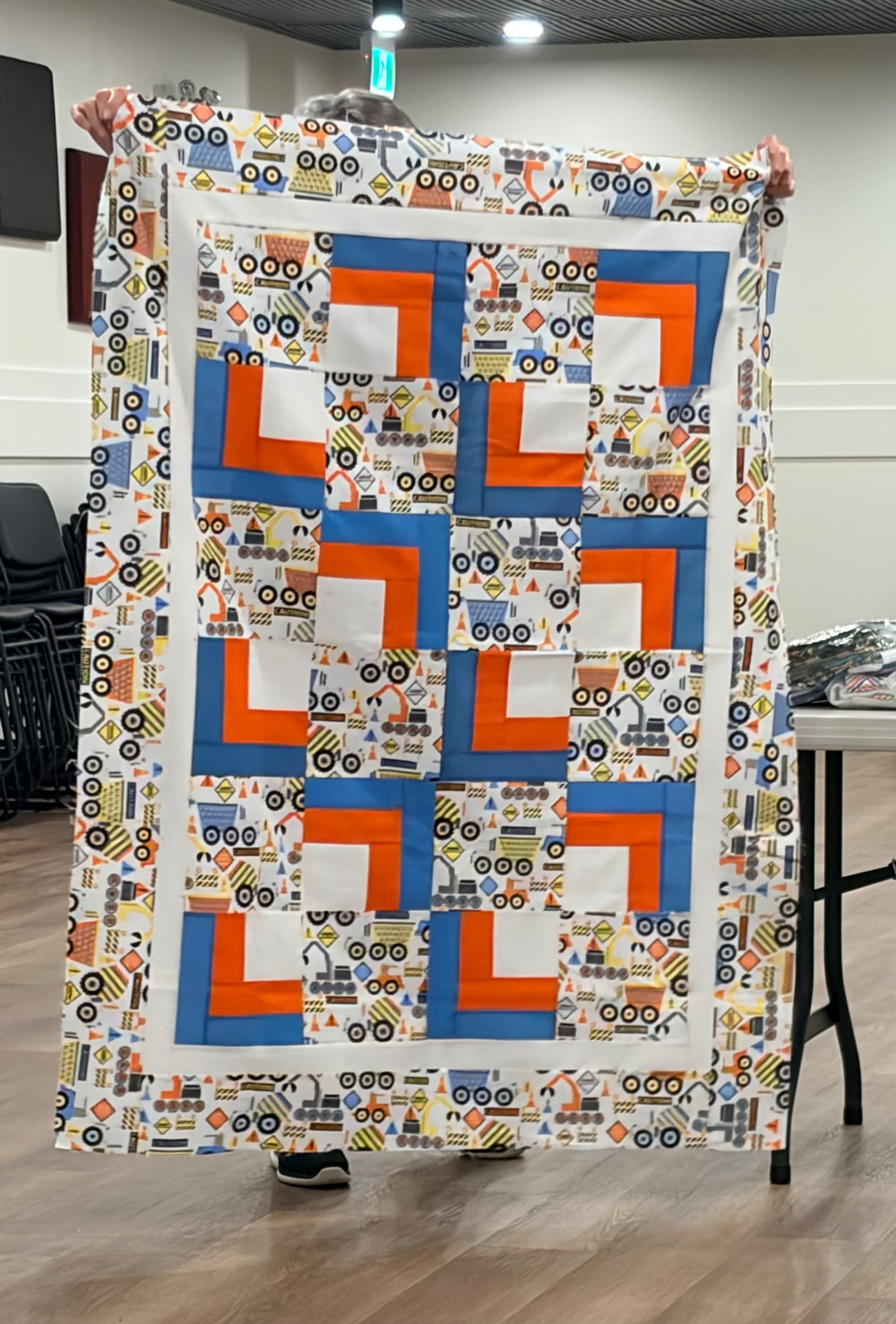 Construction-truck baby quilt with orange and blue log cabin blocks
